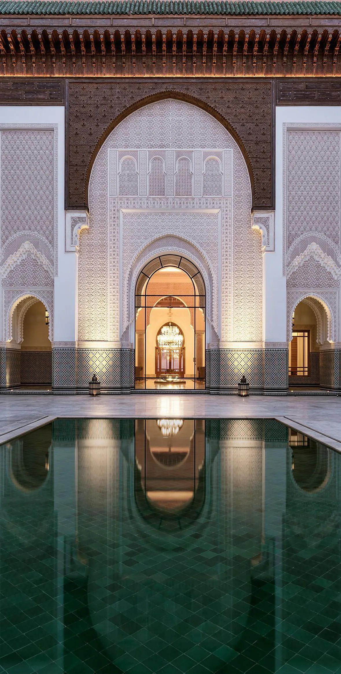 An image of a large pool of calm water situated inside a courtyard with exquisite Moorish architecture at The Oberoi hotel in Marrakech, Morocco.